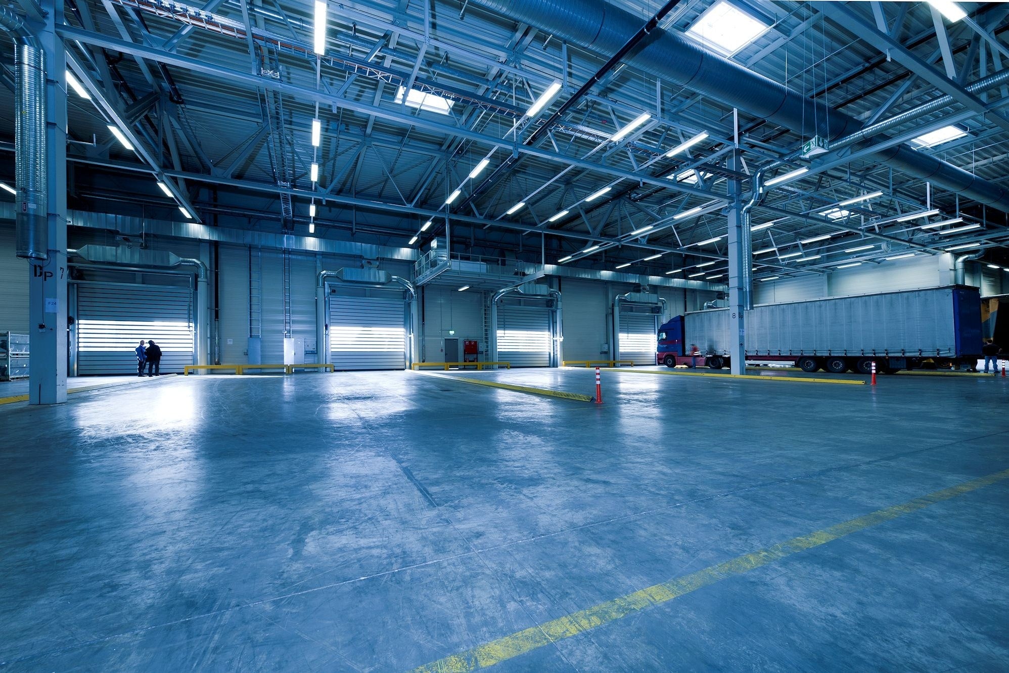 Interior view of a large, empty industrial garage with lineup of overhead and loading dock doors