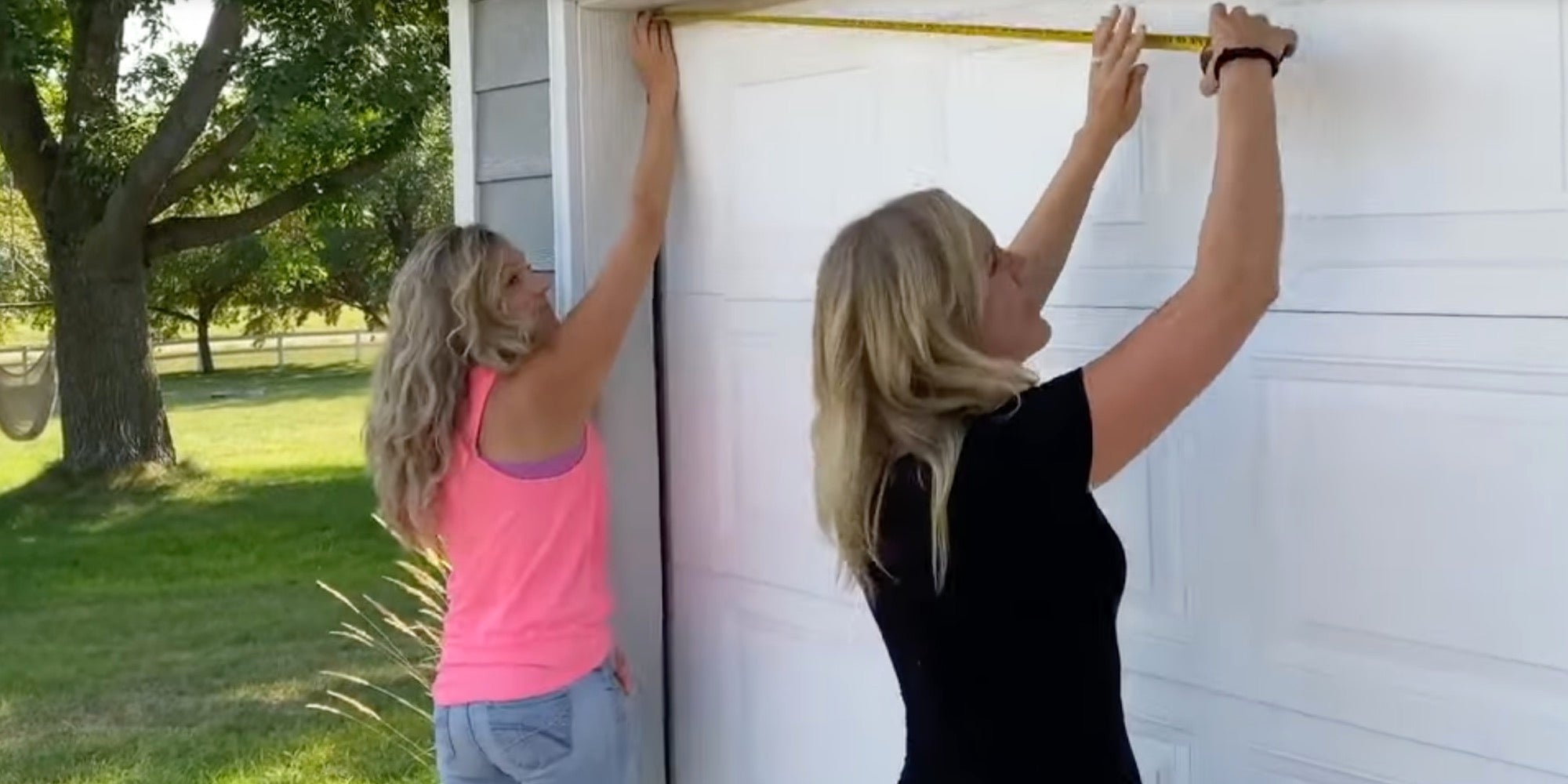 Two women stand outside and measure the width of their garage door